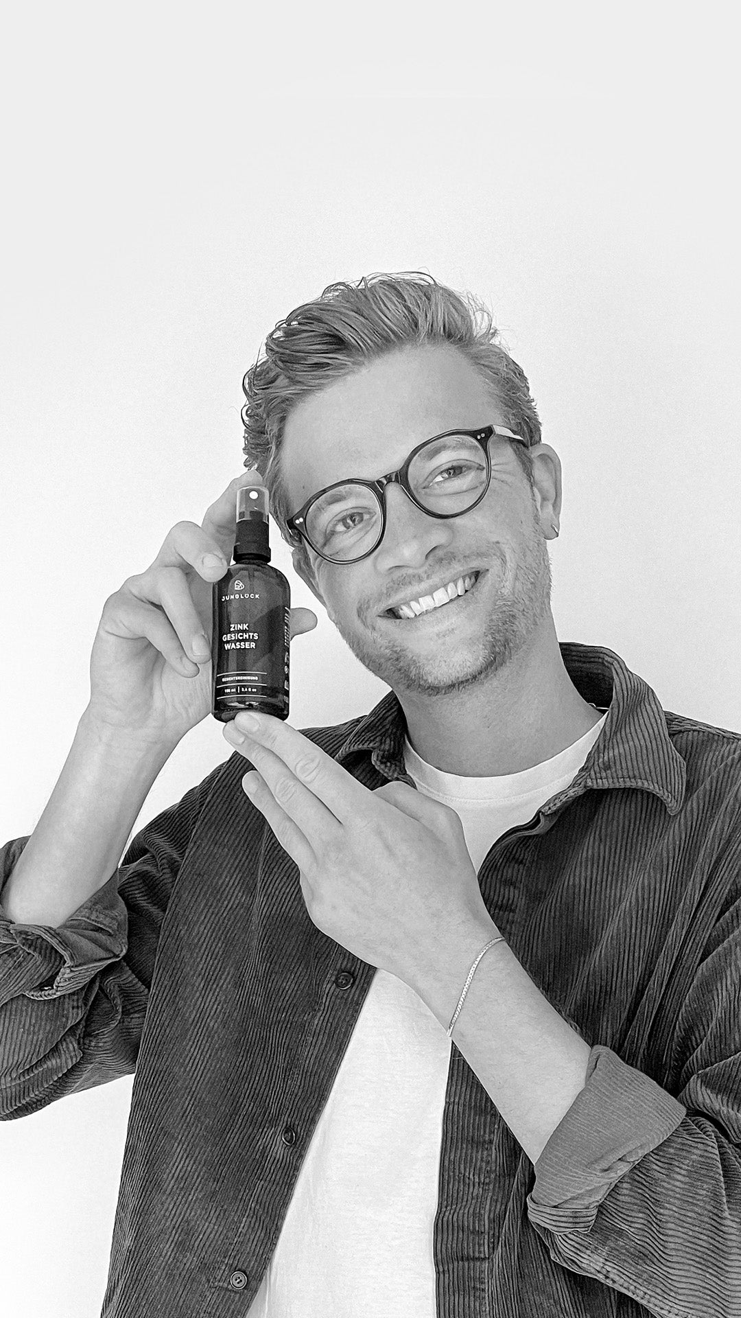 Mann hält lächelnd eine Braunglasflasche mit dem Produkt Matze in der Hand, während er in die Kamera blickt.