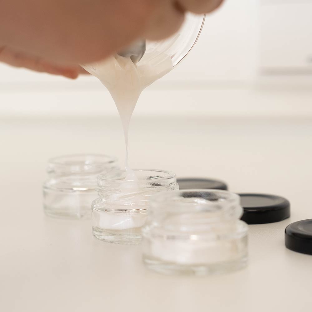 Mikro komprimierte Formulierung wird aus einem Behälter in kleine, klare Gläser mit schwarzen Deckeln gegossen.