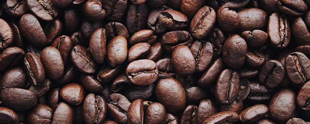 Eine nahaufgenommene Ansicht von gerösteten Kaffeebohnen in verschiedenen Brauntönen.
