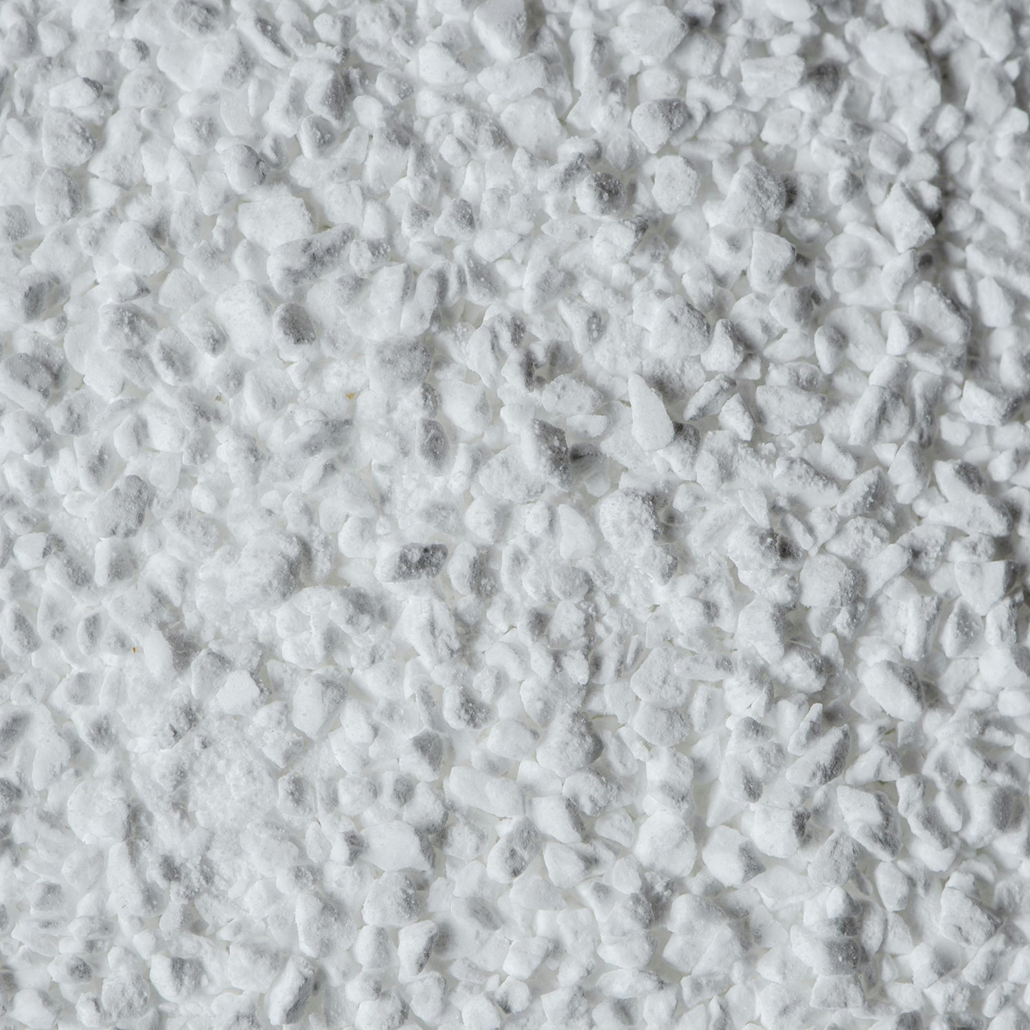 Grobkörnige, weiße Substanz, die die Textur von Zucker imitieren könnte, auf hellem Untergrund.