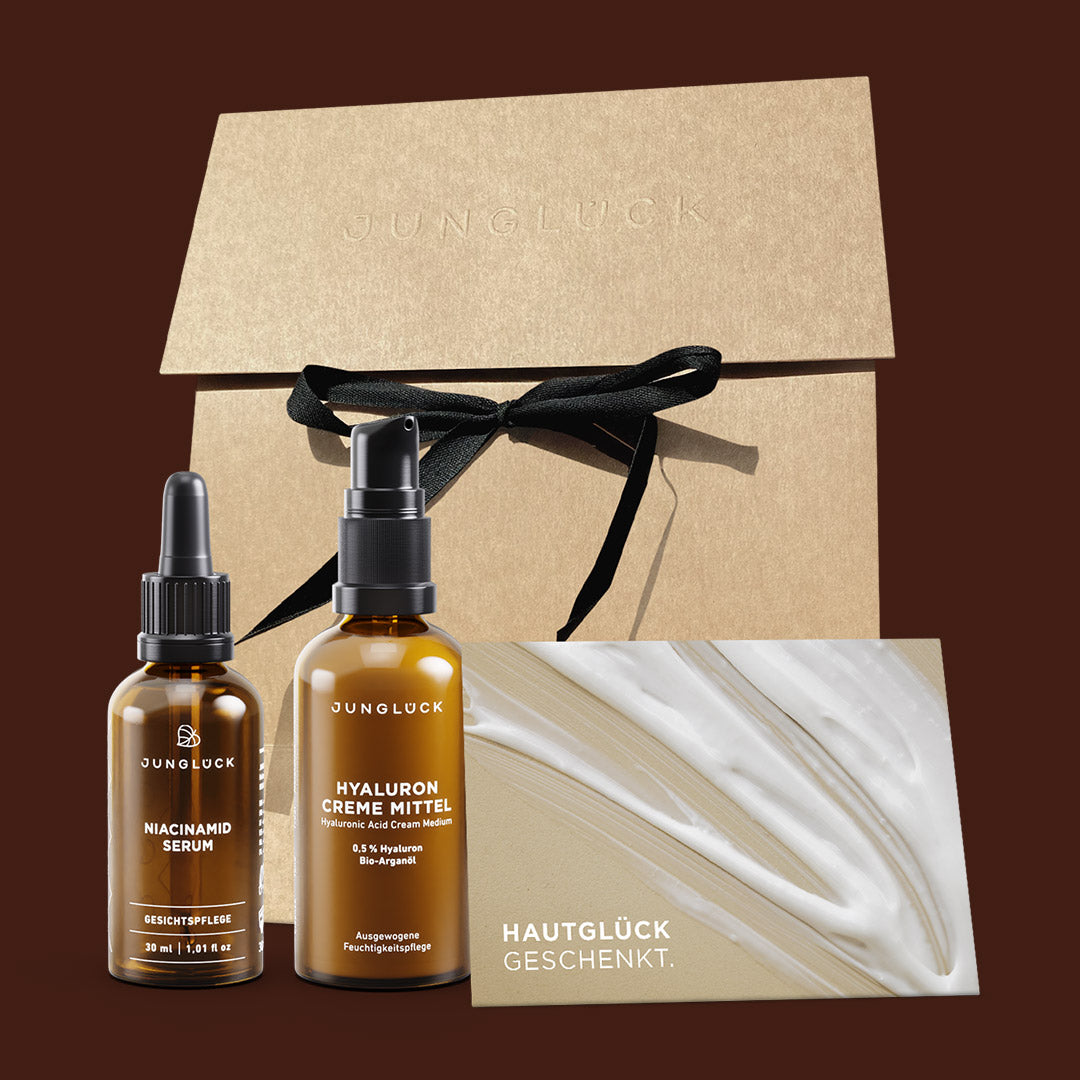 Geschenkset von JUNGLÜCK mit Niacinamid Serum und Hyaluron Creme Mittel in Braunglasflaschen, verpackt in edlem Karton mit