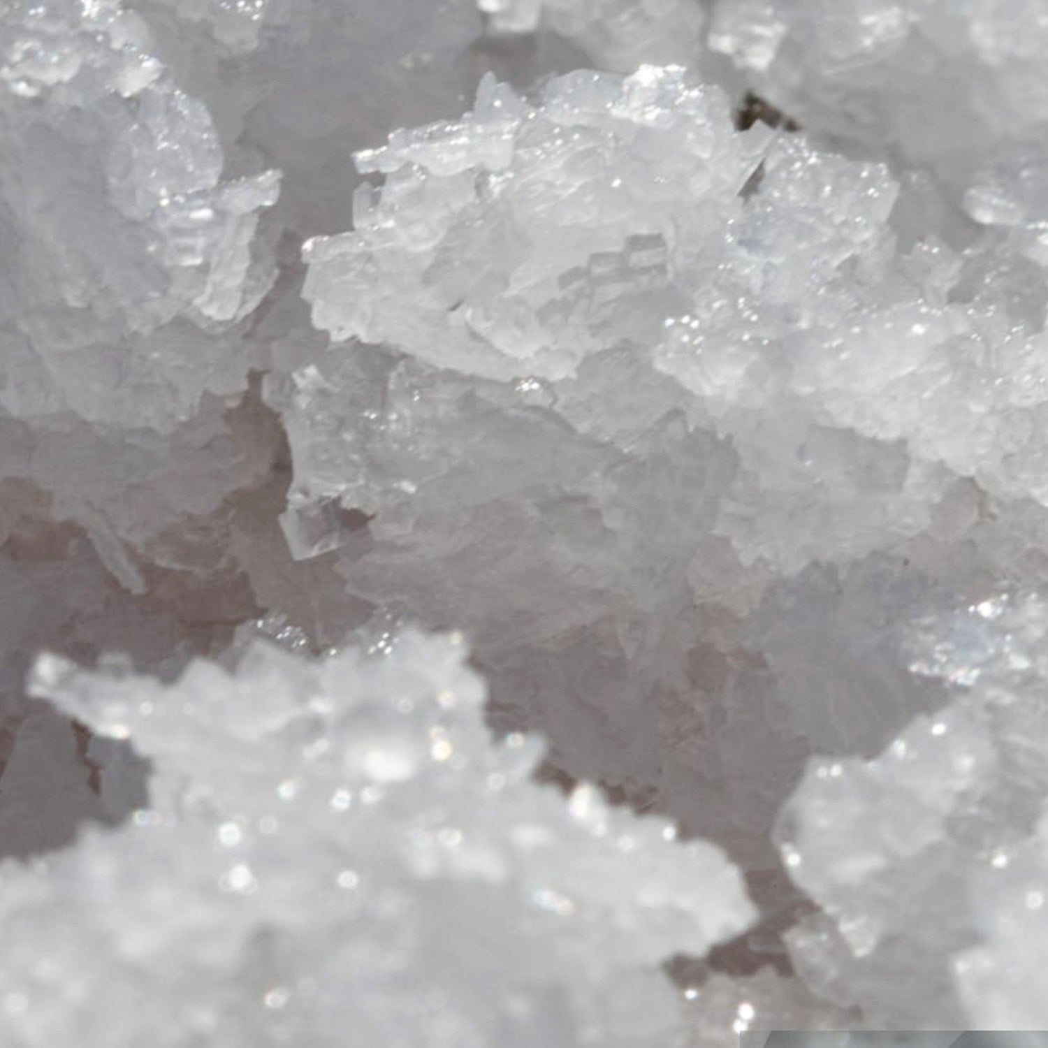 Feines, kristallines Magnesiumsalz in unterschiedlichen Größen und Strukturen, auf einer neutralen Unterlage.