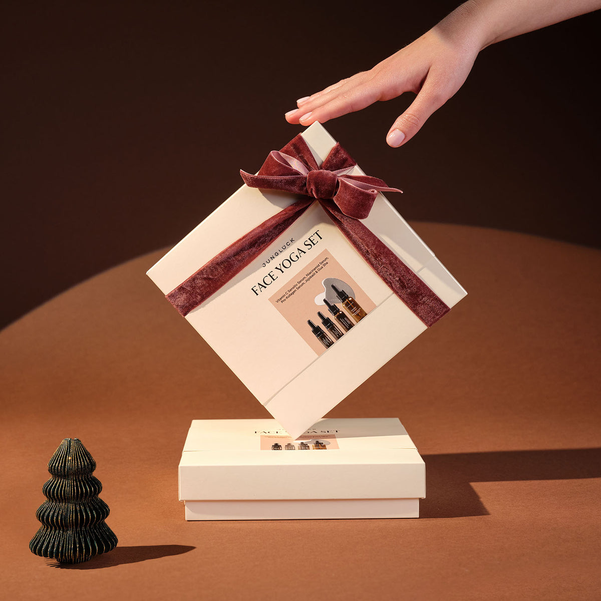 Geschenkset mit rotem Samtband, umschlossen von einer Box mit der Aufschrift 'FACE YOGA SET'. Im Hintergrund ein dekorativer