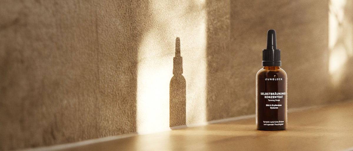 Braunglasflasche mit Pipette, steht auf einer hellen Holzoberfläche, Schatten auf der Wand.