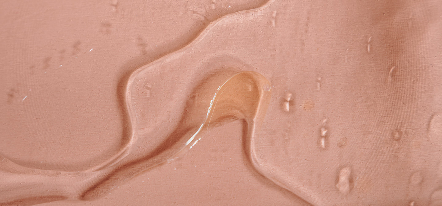 Eine sanfte, flüssige Textur in nude-rosa, schimmernd und leicht glänzend auf einem matten Hintergrund.