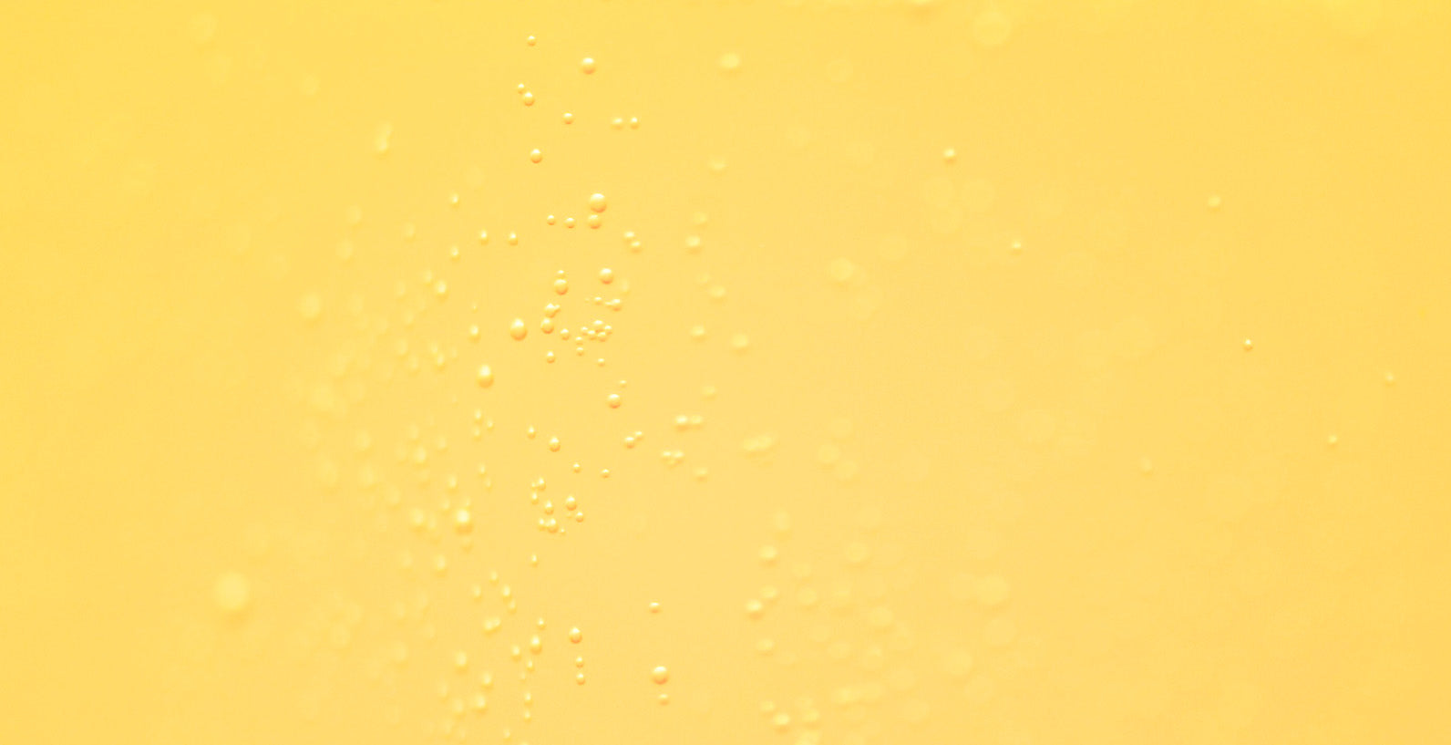 Kleckser in einem gelben Hintergrund, der an eine flüssige Textur erinnert, ideal für Hautpflege.