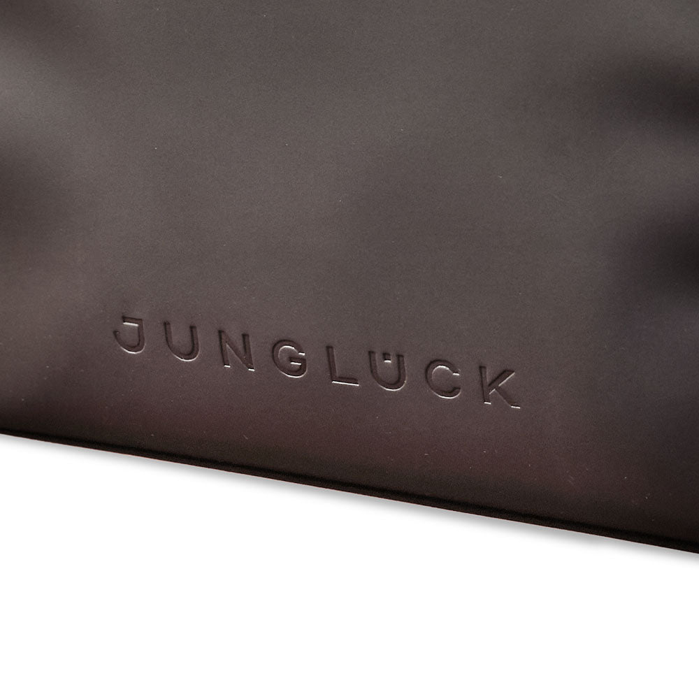 Nahaufnahme der Kosmetiktasche in dunklem Material mit eingeprägtem Schriftzug 'JUNGLÜCK'.