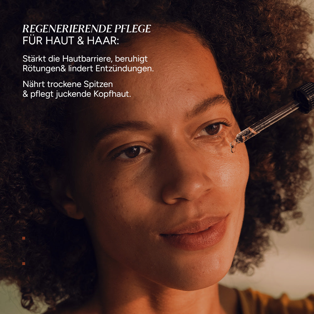Nahaufnahme einer Frau, die ein Pipettenglas mit Mandeloel hält. Der Fokus liegt auf ihrem Gesicht und der Pipette.
