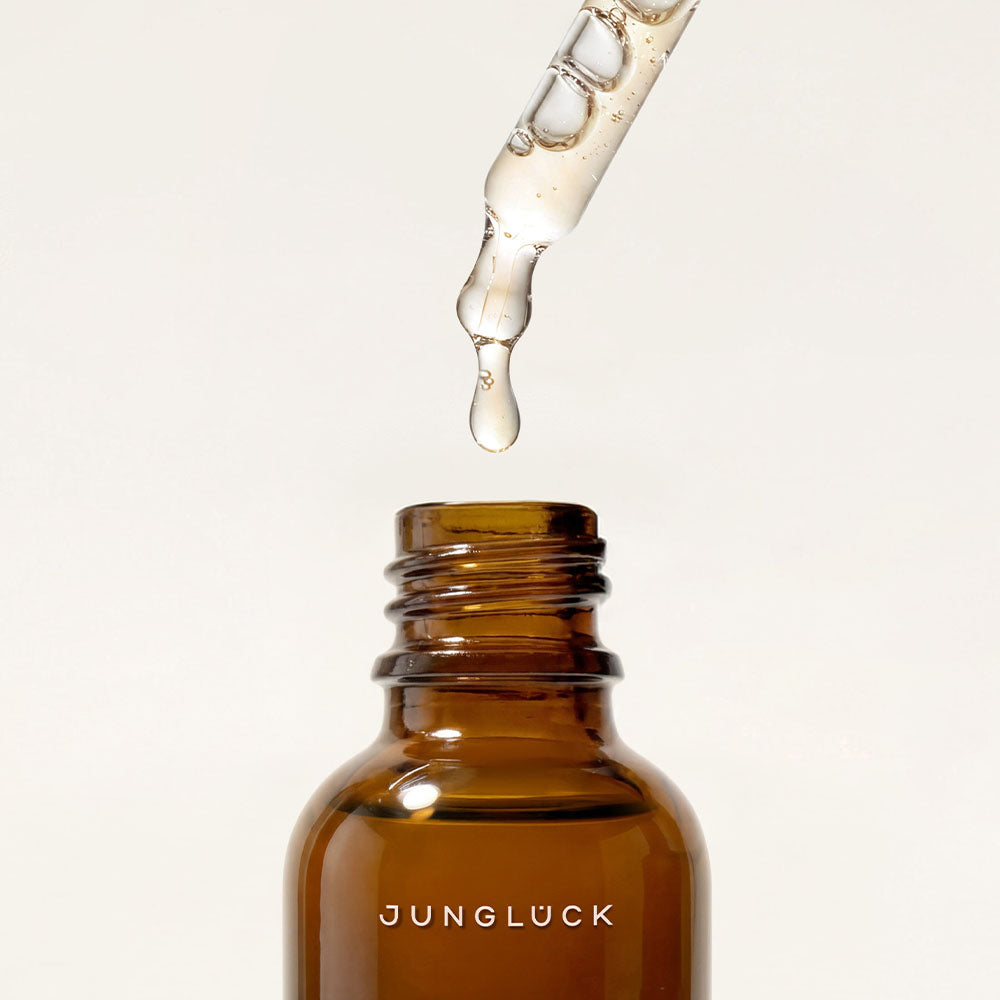 Braunglasflasche mit Pipette, aus der ein Tropfen des Vitamin C Intensiv Serums fällt.