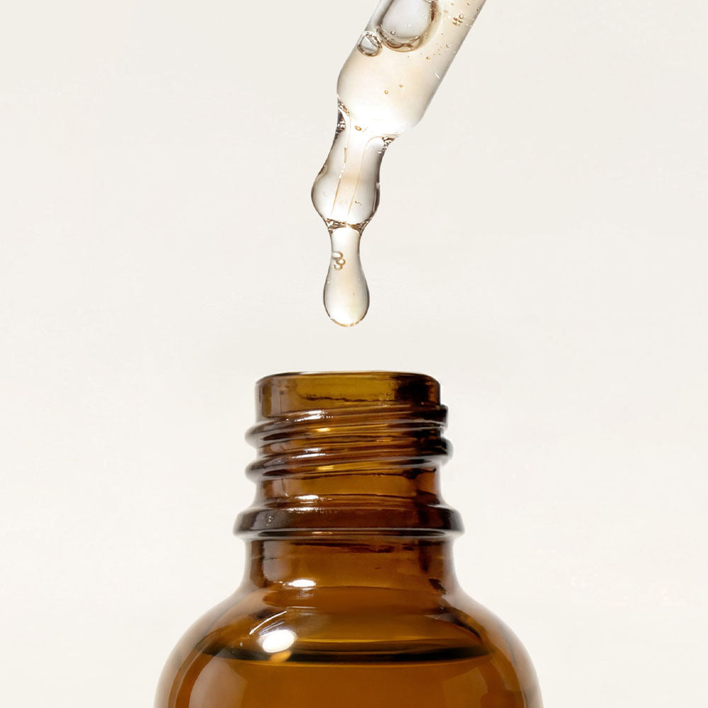 Braunglasflasche mit Pipette und Tropfen des Vitamin C Sensitiv Serums.