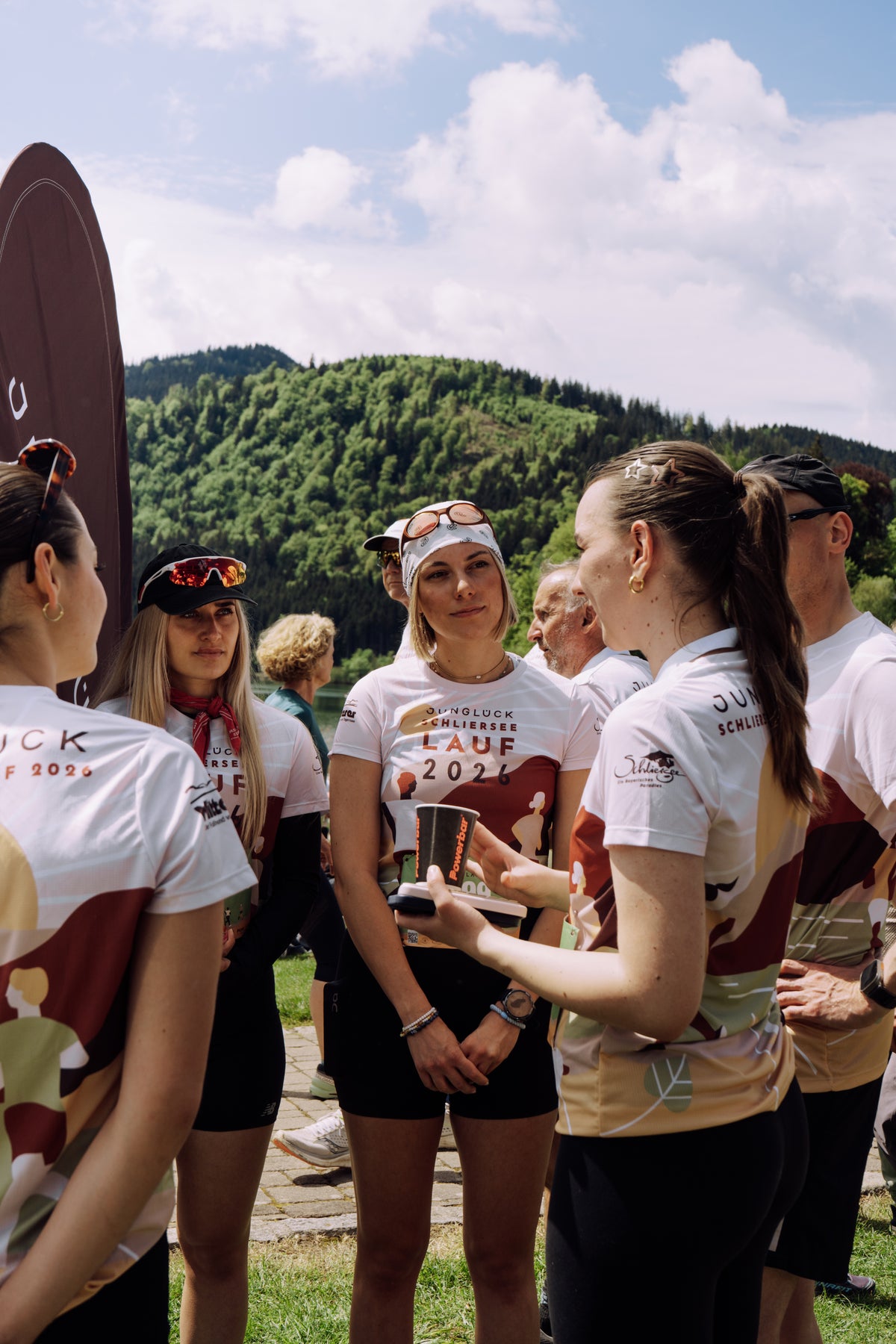 Vier Frauen in Sportkleidung des Schlierseelaufs stehen in einer Gruppe und unterhalten sich vor einer grünen Landschaft.