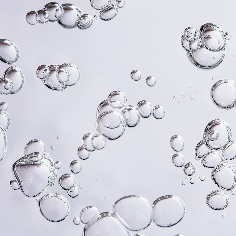 Transparente Blasen schweben in der Luft, symbolisieren Feuchtigkeit und Frische. Ein sanfter, beruhigender Hintergrund.