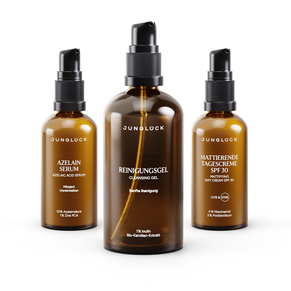 Drei JUNGLÜCK Produkte in Braunglasflaschen: Reinigungsgel, Azelainsäure Serum und mattierende Tagescreme SPF 30.