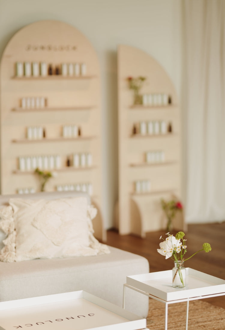 Moderne Inneneinrichtung mit zwei Regalwänden, die Braunglasflaschen und kleine Blumenvasen zeigen. Eine gemütliche Couch