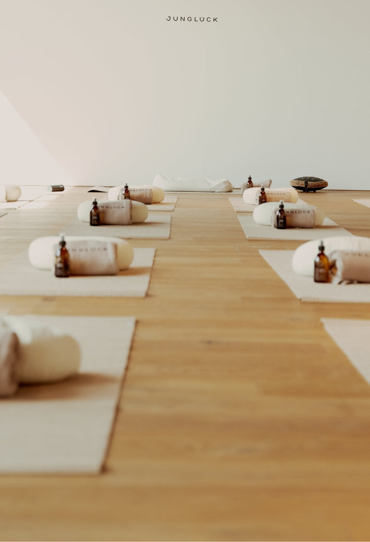 Ein heller Raum mit Holzfußboden, ausgestattet mit yogaballartigen Kissen und Braunglasflaschen, dekorativ auf Matten