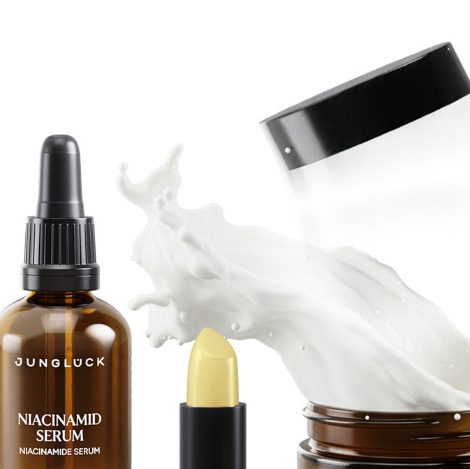 Braunglasflasche mit Niacinamid Serum, ein cremiger Inhalt spritzt daneben, dazu ein Lippenbalsam.