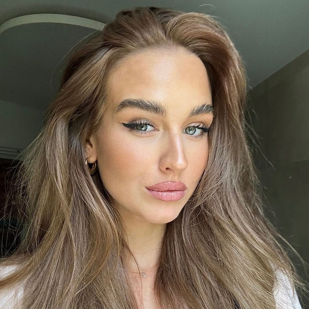 Eine Frau mit langen, braunen Haaren und einem dezenten Make-up. Ihr Blick ist selbstbewusst und entspannt.