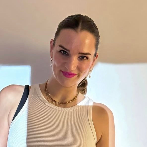 Ein lächelndes Model trägt eine schlichte, helle Oberbekleidung. Der Fokus liegt auf dem frischen Teint und den lebhaften