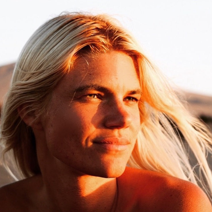 Portrait einer Frau mit langen, blonden Haaren, im sanften Sonnenlicht. Die warmen Lichtreflexe betonen ihr entspanntes